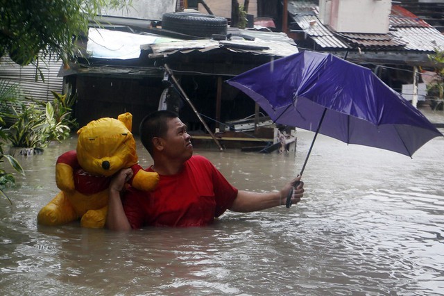 Một người đàn ông mang theo gấu bông lội trên đường ngập lụt ở Las Piñas, Philippines.