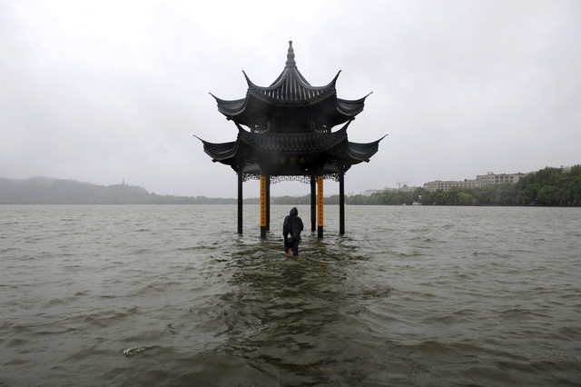 Một người đàn ông đi ra thủy đình bị ngập nước nằm giữa hồ ở Hàng Châu, Trung Quốc.