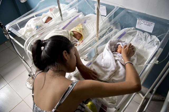 Bà mẹ trẻ của một em bé đẻ non ngủ thiếp bên cạnh con tại trung tâm y tế Eastern Visayas ở Tacloban, Philippines.