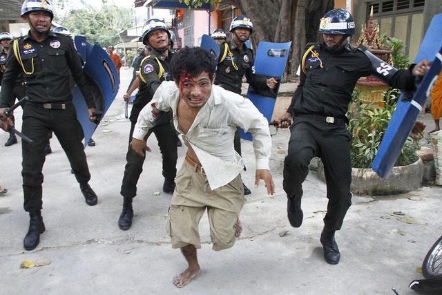 Một công nhân bị thương chạy trốn khỏi cảnh sát chống bạo động trong khuôn viên một ngôi chùa ở Phnom Penh, Campuchia.