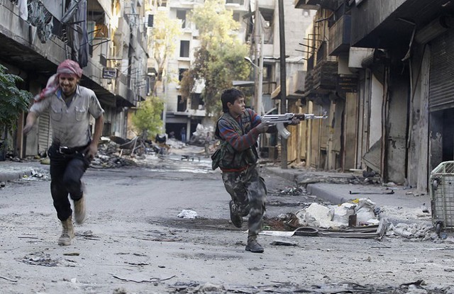 Một chiến binh 13 tuổi vừa chạy vừa bắn súng về phía lính bắn tỉa của quân đội chính phủ ở Aleppo, Syria.