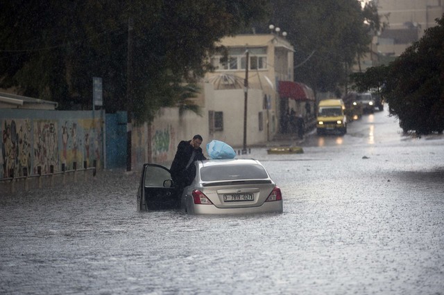 Một người Palestin gọi điện nhờ giúp đỡ sau khi chiếc xe ô tô của ông bị ngập trong nước do mưa lớn ở thành phố Gaza.