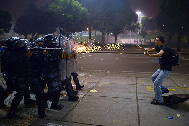 Cảnh sát chống bạo động bắn đạn cao su vào một nam thanh niên tham gia biểu tình phản đối kế hoạch tăng giá vé phương tiện công cộng tại thành phố Rio de Janeiro, Brazil.