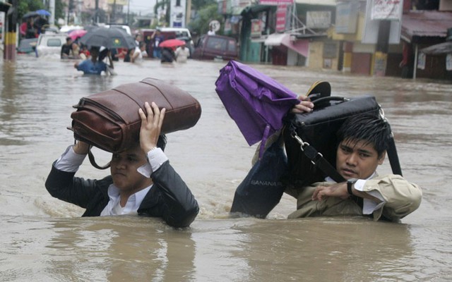 Mọi người nhọc nhằn di chuyển trên đường phố ngập nước sau nhiều ngày mưa lớn tại thủ đô Manila, Philippines.