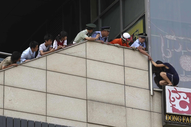 Cảnh sát đang cố gắng ngăn một phụ nữ định nhảy tự tử từ một tòa nhà cao tầng ở thành phố Bắc Kinh, Trung Quốc.