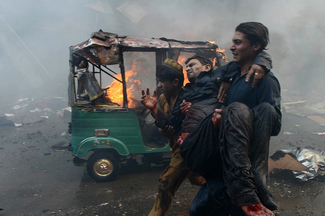 Một người đàn ông bế nạn nhân bị thương trong vụ đánh bom kinh hoàng tại Peshawar, Pakistan, khiến hàng chục người thiệt mạng.
