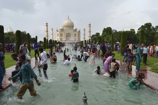 Mọi người tắm mát trong một đài phun nước lớn trước ngôi đền Taj Mahal ở Agra, Ấn Độ.