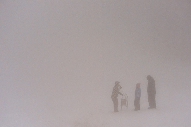 Những người trượt tuyết đứng dưới mưa tuyết và sương mù trên một ngọn núi ở Tabarz, Đức.