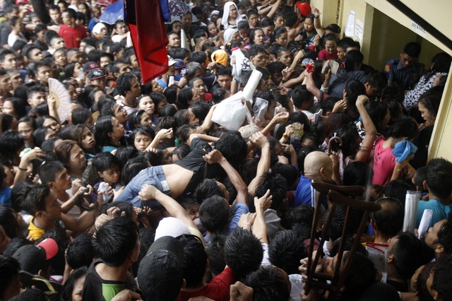 Một phụ nữ bị ngất được đám đông nhấc lên cao để đưa ra ngoài trước văn phòng Ủy ban bầu cử ở Manila, Philippines.