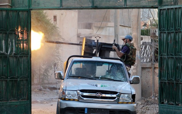 Chiến binh của lực lượng quân đội Syria tự do ngồi trên ô tô xả súng máy vào quân chính phủ trong cuộc giao tranh tại thị trấn Deir Ezzor, Syria.
