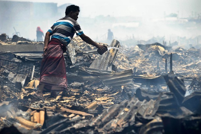 Một người đàn ông té nước vào đống đổ nát đang cháy âm ỉ sau vụ hỏa hoạn tại một khu dân cư ở miền bắc Jakarta, Indonesia.