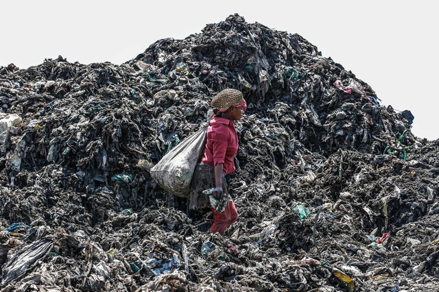 Một phụ nữ mang theo bao tải rác có thể tái chế trên bãi rác Dandora ở Nairobi, Kenya.