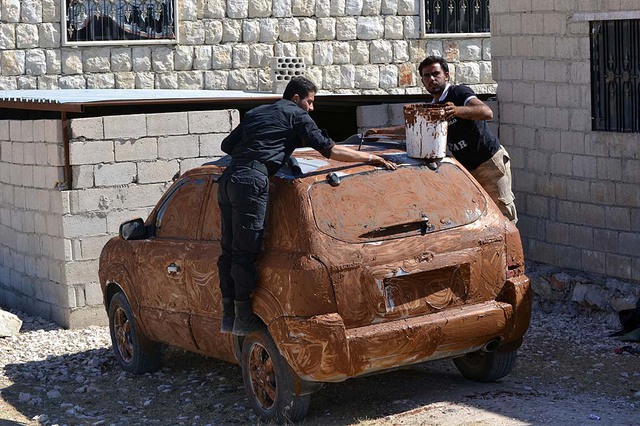 Các chiến binh phiên quân đang dùng bùn để ngụy trang ô tô tại tỉnh Idlip, Syria.