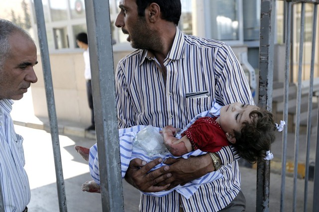 Một người đàn ông bế con gái nhỏ bị thương trong vụ nổ bom ở thị trấn Cilvegozu của Syria, gần biên giới với Thổ Nhĩ Kỳ.
