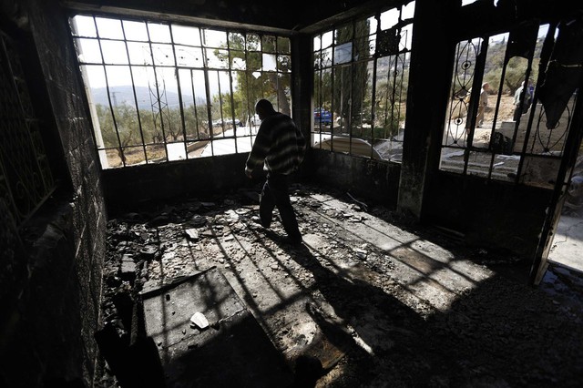 Một người Palestinia đi trong ngôi nhà của mình ở Bờ Tây, sau khi bị những người định cư Israel phóng hỏa.