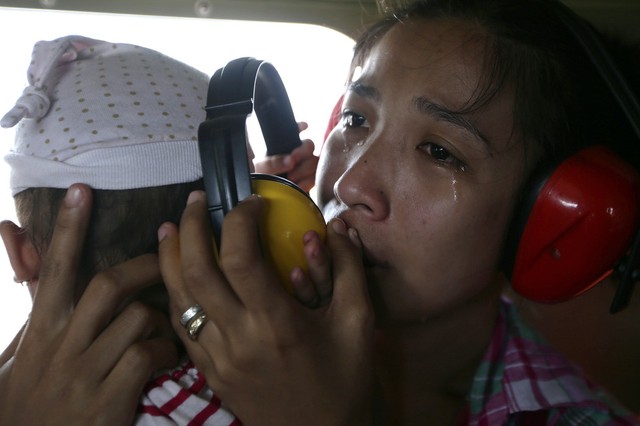 Một phụ nữ vừa ôm con vừa khóc trên máy bay quân sự để sơ tán khỏi thị trấn Guiuan, Philippines.