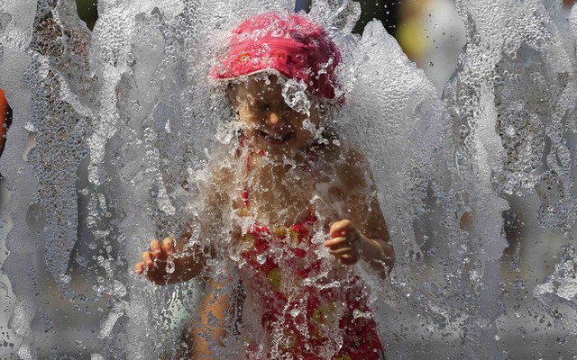 Một bé gái tắm mát trong đài phun nước dưới trời nóng 35 độ C ở Budapest, Hungary.