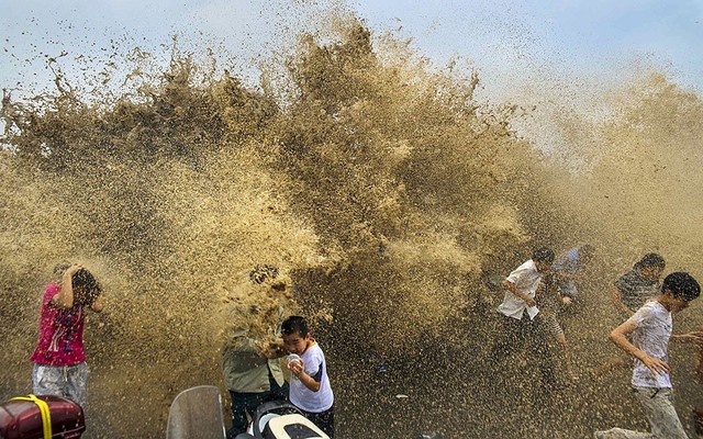 Mọi người chảy khỏi sóng triều cường trên sông Tiền Đường ở Chiết Giang, Trung Quốc.