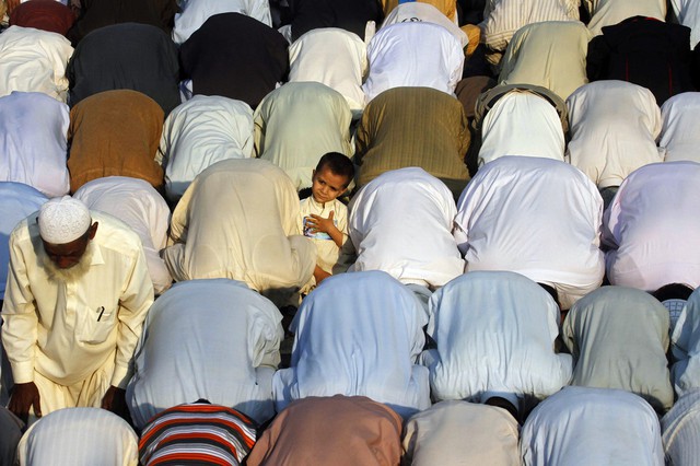 Một cậu bé đứng giữa những người cầu nguyện ở Karachi, Pakistan.