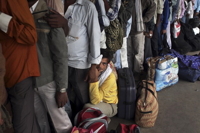 Một người đàn ông ngồi nghỉ trong khi xếp hàng chờ lên tàu hỏa ở New Delhi, Ấn Độ.