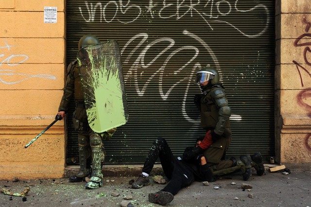 Cảnh sát chống bạo động bắt giữ một sinh viên biểu tình đòi cải cách giáo dục ở Santiago, Chile.