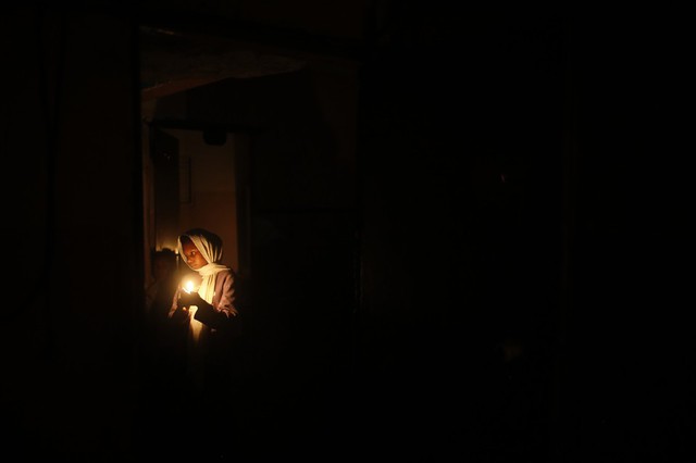 Một bé gái thắp nến trong ngôi nhà do tình trạng mất điện tại thành phố Jabalya, Dải Gaza.