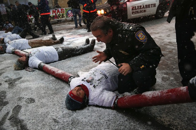 Người biểu tình nắm tay nhau nằm dưới mưa tuyết trước lối vào một trung tâm giam giữ người nhập cư ở Elizabeth, Mỹ.