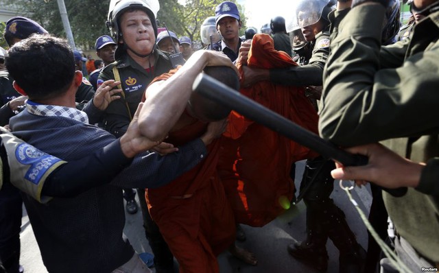 Một nhà sư tự vệ khi bị cảnh sát tấn công trong cuộc biểu tình trước hội trường thành phố ở Phnom Penh, Campuchia.