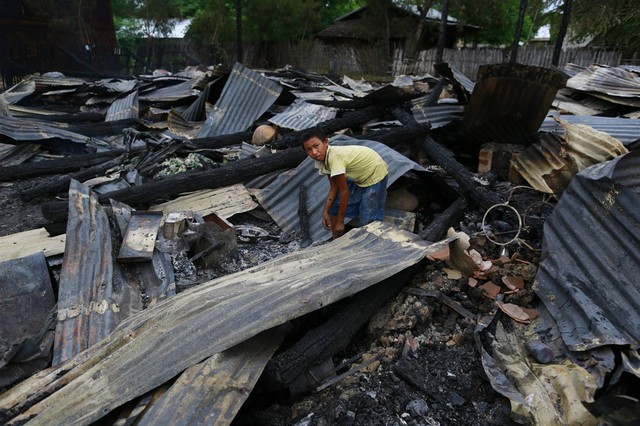 Một cậu bé tìm kiếm đồ còn dùng được giữa những ngôi nhà bị cháy rụi ở Htan Kone, Myanmar.