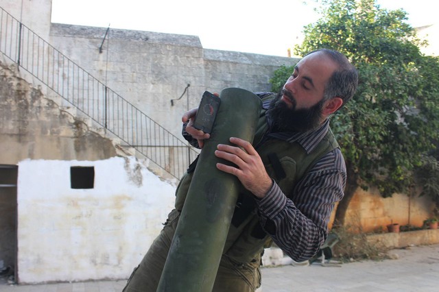 Chiến binh phiến quân Syria dùng điện thoại di động để chỉnh góc bắn cho một ống phóng đạn cối ở thành phố Aleppo.