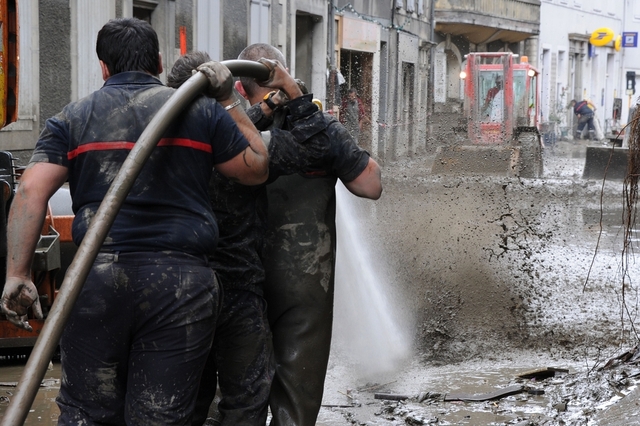 Lính cứu hỏa phun nước để rửa sạch một đường phố đây bùn sau khi nước lũ rút đi ở thành phố Saint-Béat, Pháp.