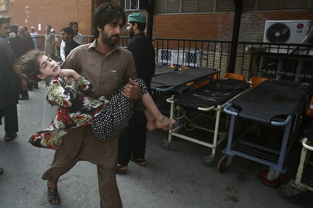 Người đàn ông bế một cô gái bị thương trong vụ đánh bom ở Peshawar, Pakistan.