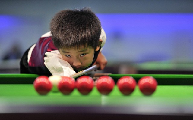 Cậu bé Wang Wuka, 3 tuổi, luyện tập trước khi chơi bi-a tay cơ từng 7 lần vô địch thế giới Stephen Hendry tại Bắc Kinh, Trung Quốc.