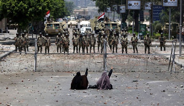 Hai phụ nữ ngồi biểu tình trước hàng rào dây thép gai được quân đội Ai Cập dựng lên trên đường phố ở thủ đô Cairo.