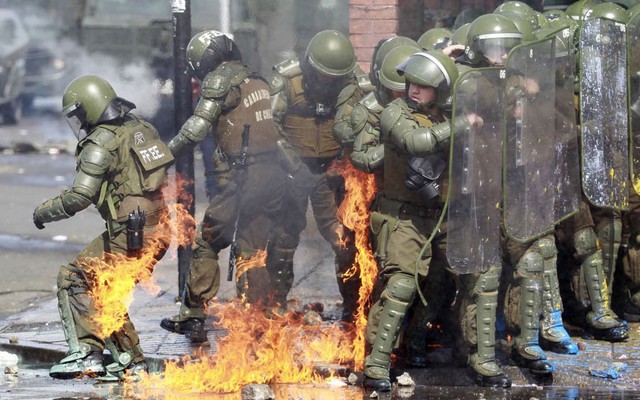Cảnh sát chống bạo động bị bắt lửa sau khi bị người biểu tình ném bom xăng tự chế tại thành phố Santiago, Chile.