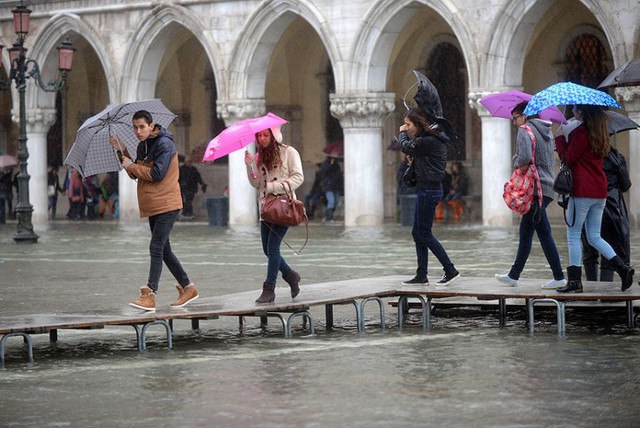 Du khách đi trên chiếc cầu tạm tại quảng trường St Mark bị ngập lụt ở thành phố Venice, Italia.