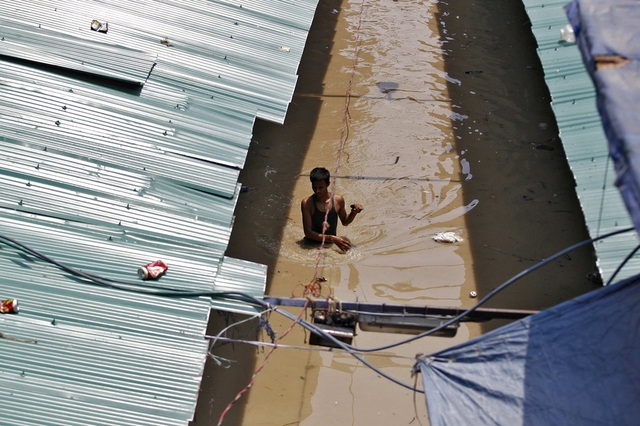 Một người đàn ông lội trong nước lũ đục ngàu tại một khu chợ ở New Delhi, Ấn Độ.