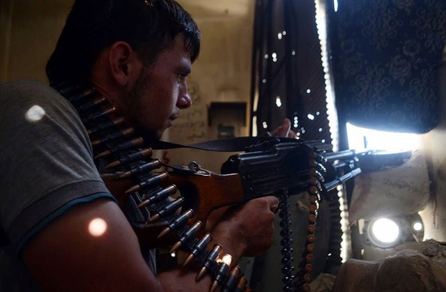 Một chiến binh của lực lượng phiến quân nhắm súng về phía quân chính phủ ở Aleppo, Syria.