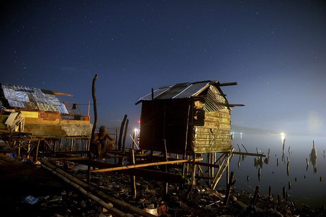 Một người đàn ông ngồi trên ngôi nhà bị phá hủy dọc bờ biển ở Tacloban, Philipines.