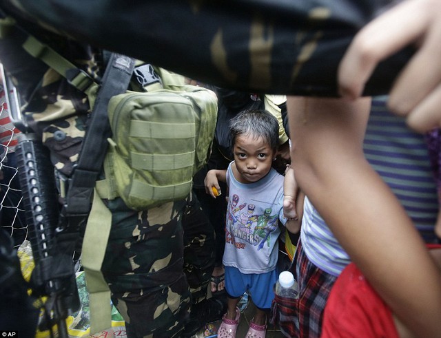 Một cậu bé bám chặt lấy người thân khi bị các binh sĩ ngăn tại sân bay.