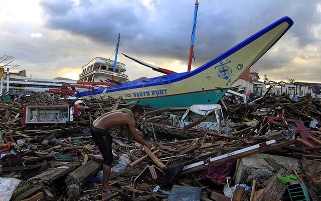 Một người đàn ông tìm kiếm những thứ còn dùng được trong đống đổ nát gần một con tàu ở thành phố Tacloban, Philippines.