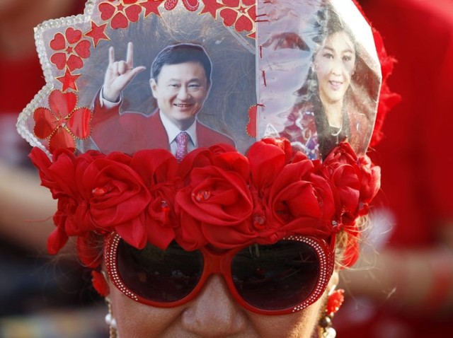 Một người biểu tình của phe Áo đỏ đội mũ với chân dung của cựu Thủ tướng Thái Lan Thaksin Shinawatra  và nữ Thủ tướng Yingluck Shinawatra trong cuộc diễu hành ủng hộ chính phủ hiện tại ở Bangkok.