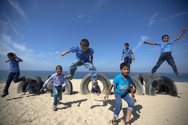 Học sinh Palestin chơi với lốp xe ô tô trên bãi biển Gaza ở Deir al-Balah.