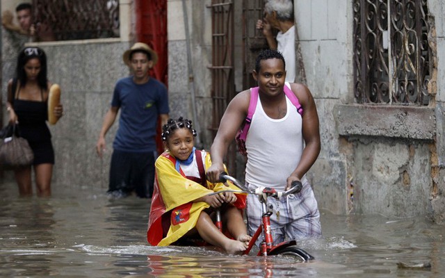 Một người đàn ông dắt xe đạp chở bé gái trên đường phố ngập lụt ở Old Havana, Cuba.