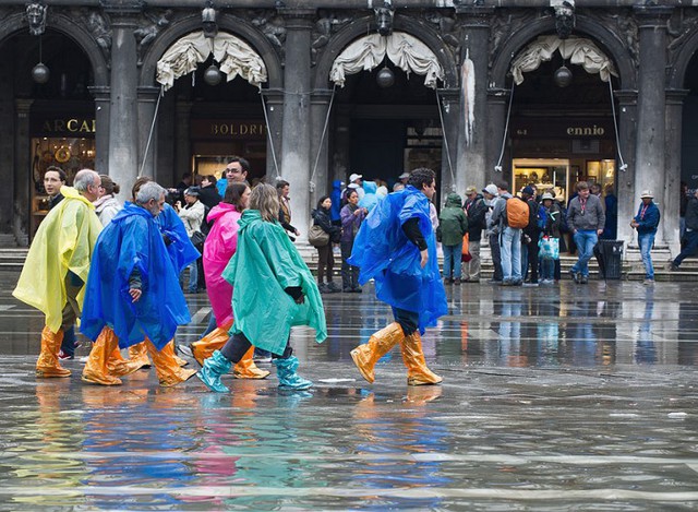 Du khách mặc áo mưa và ủng ni lông đi trên quảng trường Saint Mark ở Venice, Italia.