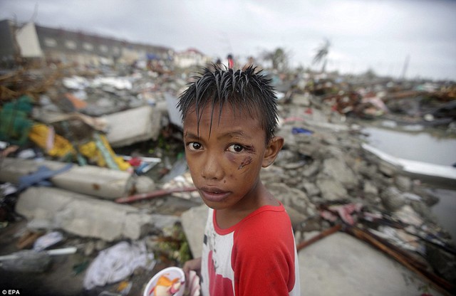 Cậu bé Joshua Cator, 11 tuổi, tìm kiếm thức ăn và những thứ còn dùng được trong những ngôi nhà đổ nát sau siêu bão Haiyan tại thành phố Tacloban, Philippines.