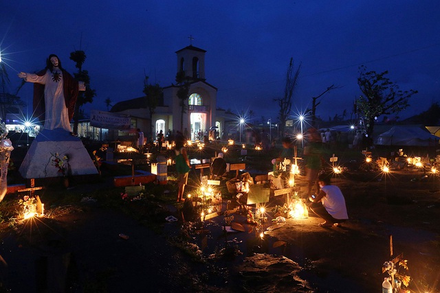 Mọi người tới thăm mộ người thân trong đêm Giáng sinh tại một nghĩa trang tập thể bên ngoài một nhà thờ ở San Joaquin, Philippines.