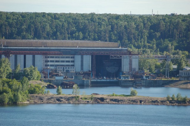 
	Nhà máy nằm bên dòng sông Volga, nước Cộng hoà Tatarstan (thuộc Nga). Vị trí của nhà máy được ví như trái tim của nước Nga, có thể dễ dàng cung cấp tàu đến biển Đen, biển Caspi, biển Baltic hay biển Trắng nhờ con đường nội thuỷ (Trong ảnh: Nhà máy nhìn từ sông Volga.)