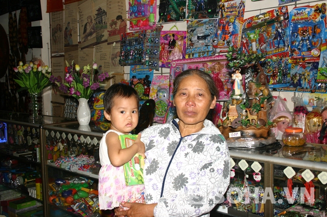 Bà Phạm Thị Huệ, bế đứa cháu ngoại trên tay, thể hiện rõ sự lo lắng cho tương lai của bé.