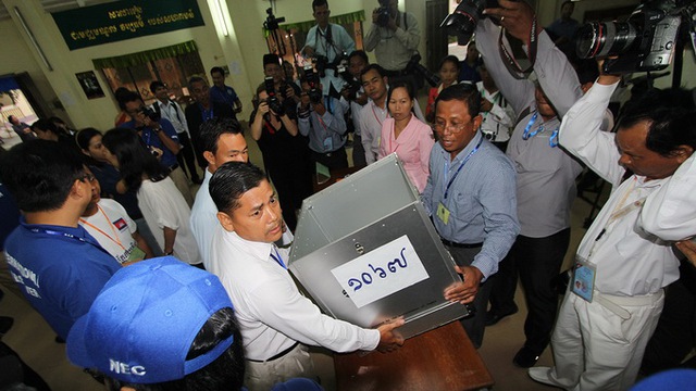 
	Các nhân viên phục vụ bầu cử giơ thùng phiếu rỗng ra để đoàn quan sát viên quốc tế xem trước